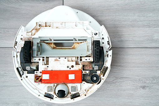 Repairing a robot vacuum cleaner that is clogged with dirt and hair. Disassembled robot vacuum cleaner. the concept of repairing home electronics