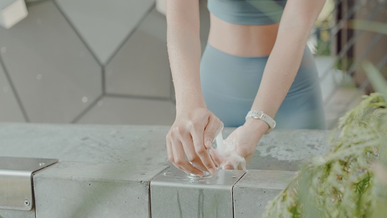 Young Asian woman washing her hands after workout in the park public restroom