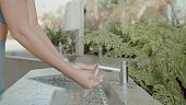 Young Asian woman washing her hands after workout in the park public restroom