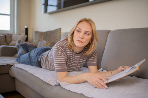 istock Woman reading book at home 1719676567