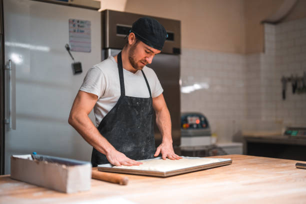 istock Caucasian Artisan Baker Shaping Dough On A Baking Tray 1719690320