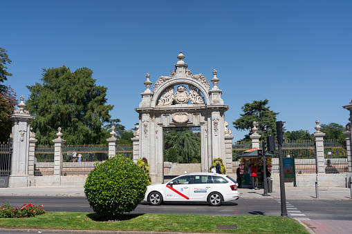 Taxi passing in front of the Felipe IV Gate, one of the entrances to the Buen Retiro public park in the Spanish capital. Madrid. Spain. July 28, 2023.