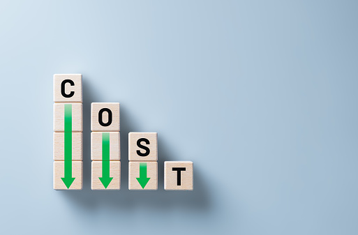 Lean and Cost reduction concept. Decreasing company expenses to maximize profits. Stacked wooden cube with word cost and green down arrows. Business improvement, manufacturing optimization management.