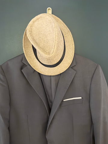 Chic menswear with fedora hat and suit hanging on a wall