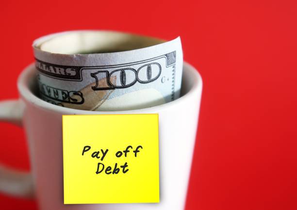 istock A yellow sticky note written Pay off Debt on white ceramic cup with cash dollars money inside, isolated on red backgroun. Concept of Debt Free plan / smart money management 1719767961