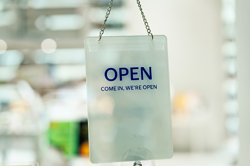 View through window of open sign in shop