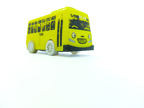 A yellow toy bus made of plastic on a white background