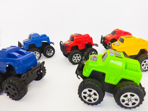 A collection of off-road toy cars made of green, blue, red and yellow plastic on a white background