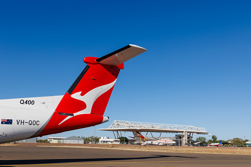 Longreach, Queensland - 29 June 2021: QantasLink Bombardier DHC-8 on the tarmac at Longreach Airport (LRE) in outback Queensland with the Qantas Museum in the background