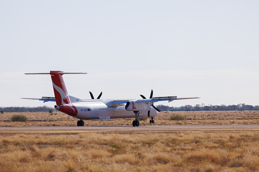 Longreach, Queensland - 29 June 2021: QantasLink Bombardier DHC-8 taxiing on the runway at Longreach Airport (LRE) in outback Queensland