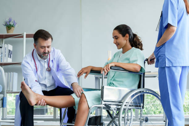 lekarz ortopeda podnoszący nogę hiszpańskiej pacjentki na wózku inwalidzkim. podnieś nogę w górę iw dół, aby sprawdzić, czy nie ma obrażeń. aby przygotować się do fizykoterapii z fizjoterapeutą. - doctors office adult break caucasian zdjęcia i obrazy z banku zdjęć