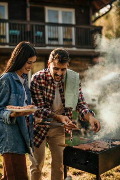 istock Two people share a delightful BBQ experience, with the grill master expertly flipping meat while his partner adds a flavorful touch. 1719908029