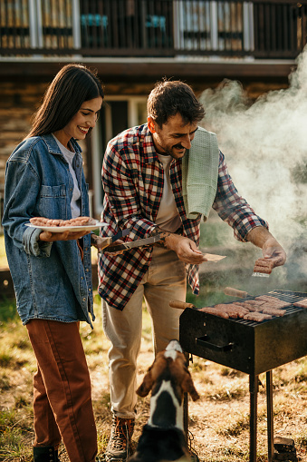 Two people share a delightful BBQ experience, with the grill master expertly flipping meat while his partner adds a flavorful touch.
