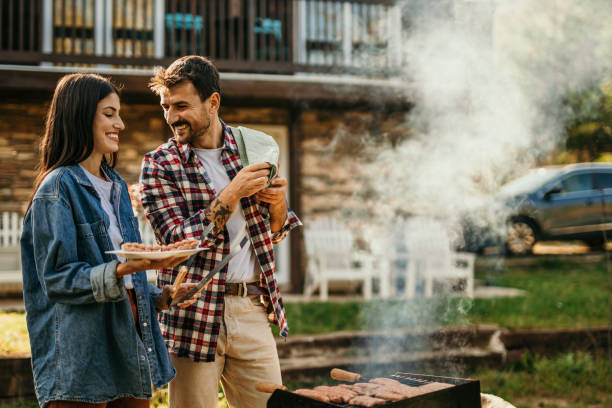 istock Two people share a delightful BBQ experience, with the grill master expertly flipping meat while his partner adds a flavorful touch. 1719908032