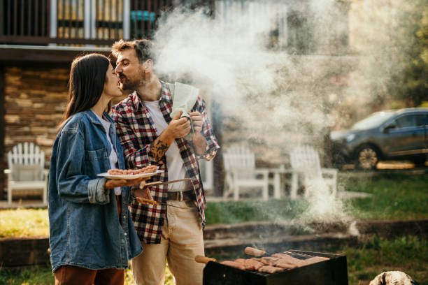 istock Two people share a delightful BBQ experience, with the grill master expertly flipping meat while his partner adds a flavorful touch. 1719908561
