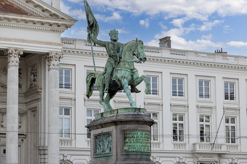 Brussels, Belgium - May 18, 2023: Statue of Godfrey of Bouillon at The Place Royale known as Koningsplein. Neoclassical Church of St. James on Coudenberg in a distance