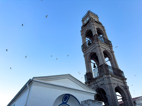 Virgin Mary Church. Bozcaada church clock tower. No people. Seagulls.