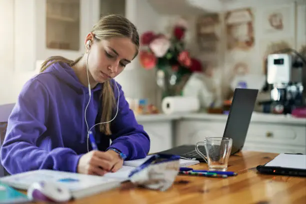 Photo of Teenage girl using laptop to do homework at home