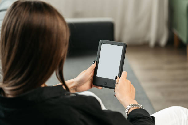 istock Young woman sitting the couch with an e-book 1720003384