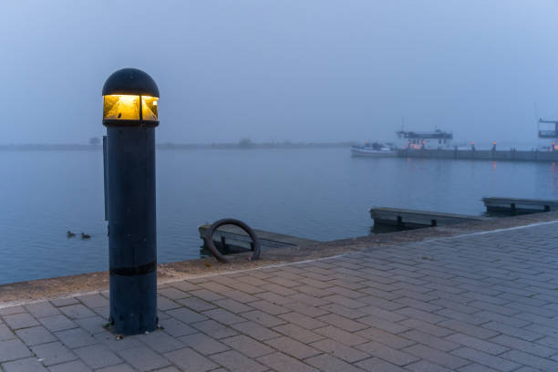 Bollard light in a harbor on a blue misty morning