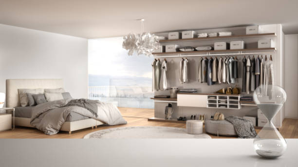 istock White table or shelf with crystal hourglass measuring the passing time over minimalist stylish bedroom with panoramic windows, architecture interior design, copy space background 1720026363