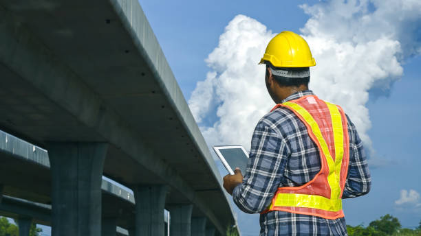 istock Asian foreman using tablet to record electronic data on construction site of concrete highway bridge. Inspection project road construction development. 1720039289
