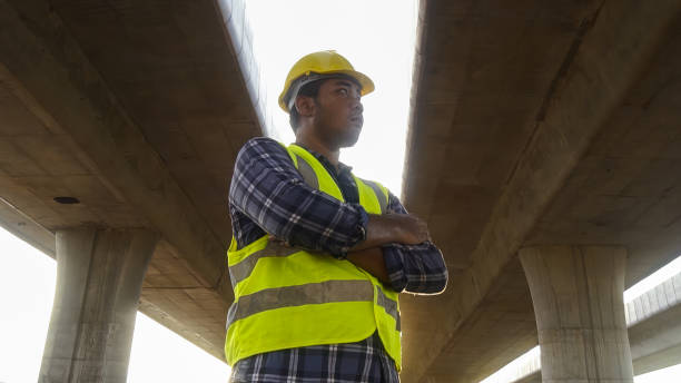 istock Close up face Asian foreman check work on construction site of concrete highway bridge. Inspection project road construction development. 1720039319