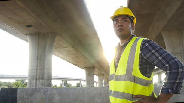 istock Close up face Asian foreman check work on construction site of concrete highway bridge. Inspection project road construction development. 1720039876