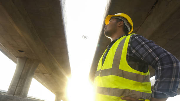 istock Close up face Asian foreman check work on construction site of concrete highway bridge. Inspection project road construction development. 1720040786