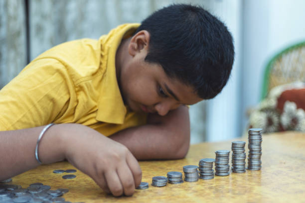 istock Portrait of Indian child putting coins to the stack 1720073142