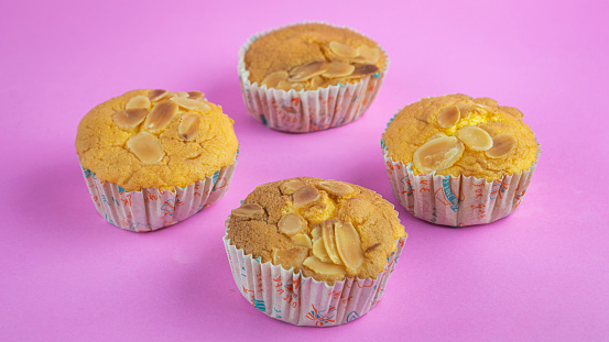 Soft, sweet, delicious almond cupcakes on a pink background.