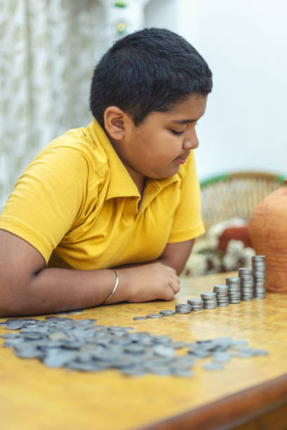 istock Portrait of Indian child putting coins to the stack 1720084681