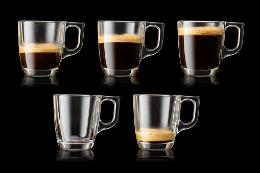 Set of different filled transparent glass mugs with espresso coffee on black background with clipping path.