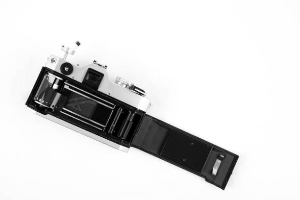 Detail photo of a metal-bodied analog camera and 35mm film taken in a light box with studio light effect