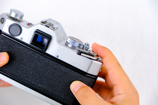 Old camera with tape and cap. Vintage black and silver camera, film tape and plastic cap isolated on white background.