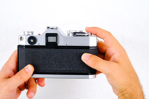 Detailed photograph of 35mm film shot in a lightbox with a studio light effect of a metal-bodied analog camera and its lens