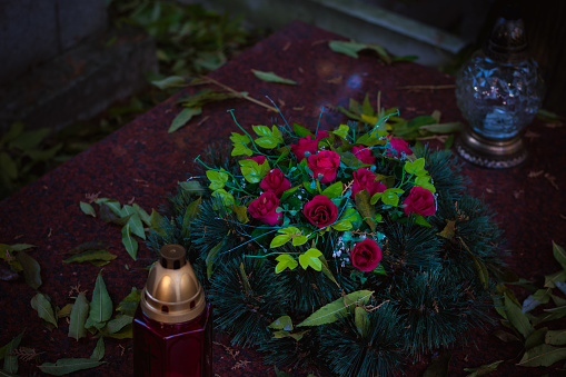 grave decorated with lantern, candles, chrysanthemum flowers during All souls day, sad and peaceful atmosphere