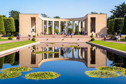 Colleville-sur-Mer, France - Sept. 5, 2023: Front view of the memorial in the Normandy American Cemetery, a World War II military cemetery located near Omaha beach, mirroring in the reflecting pool.