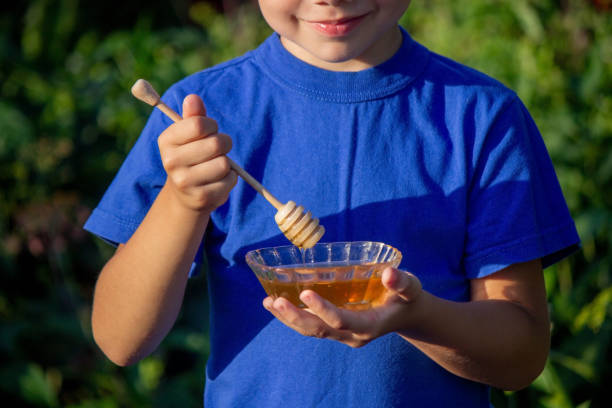 istock boy eats honey in a flower garden. Selective focus. 1720141337