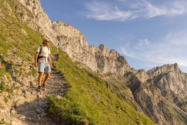 Man hikes along grassy mountain ridge at sunrise