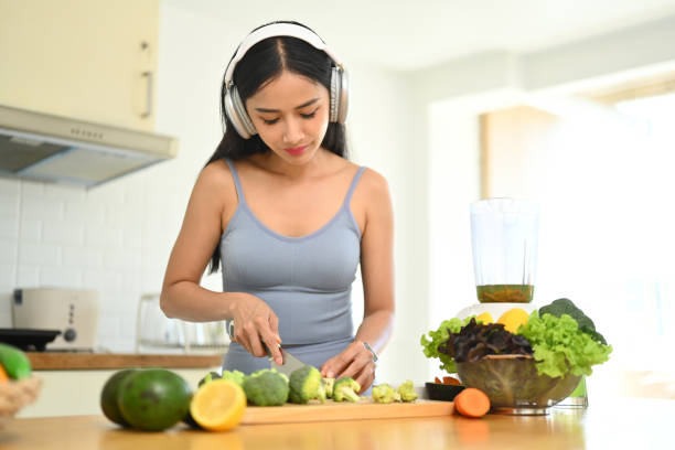 istock Pretty young woman preparing ingredients for making vegetables smoothie in kitchen. Dieting, healthy lifestyle concept 1720144124