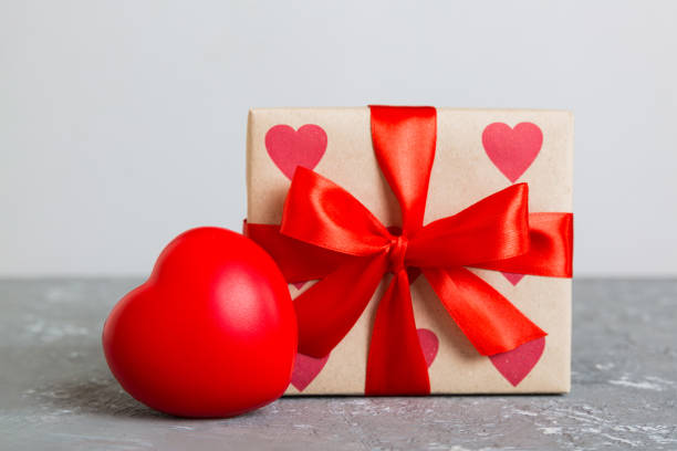 istock gift box with red bow and red heart on colored background. Perspective view. Flat lay 1720144584