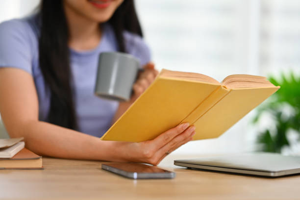 istock Calm young woman drinking tea and reading book at home. Education, knowledge and leisure activity concept 1720146974