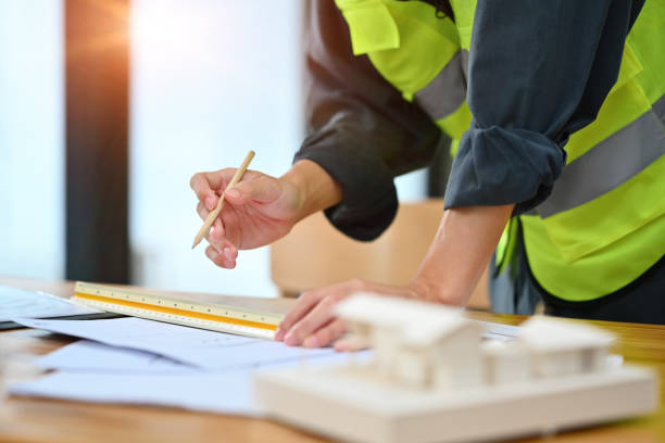 istock Civil engineer, architect male standing at desk with house model and working with blueprints 1720157766