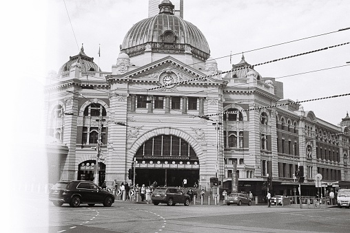 Traffic in front of Flinders Street Station. Photo taken on black and white film. Artistic light flare on film to the left of frame.