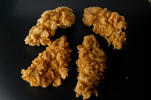Crispy fried chicken isolated on black background. Fresh crunchy fried chicken on a white plate. Delicious hot and crispy fried chicken. Image about food of fast food restaurant.