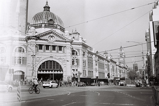 Bicycle, cars, traffic and people outside Flinders Street Station. Photo taken on black and white film.