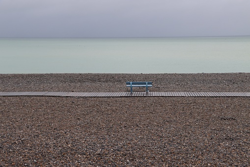 Sous un ciel menaçant et temps pluvieux, banc de couleur sur la plage du Tréport en Normandie