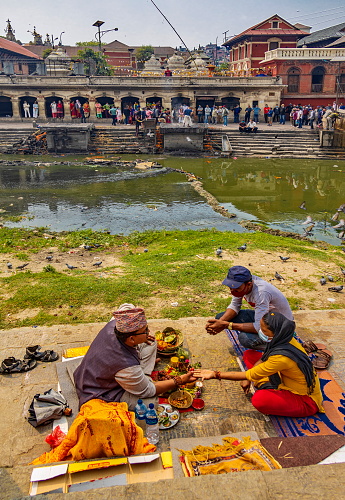 Pashupatinath, Kathmandu, Nepal - April 19, 2022: Palmistry teller at Bagmati river, where the Hindu ceremony of cremation takes place. Nepalis from all over the country arrive there to spend the last days of their lives and then the ritual of cremation is followed by relatives and priests.