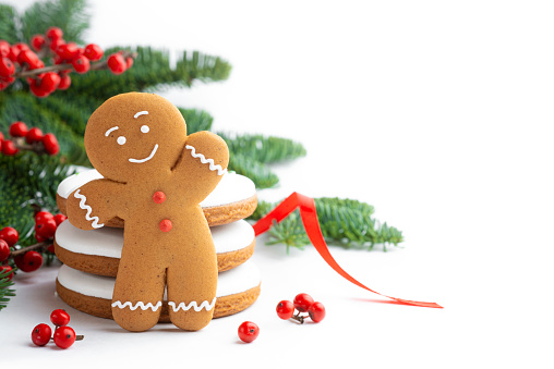 Homemade gingerbread man cookies and Christmas tree decorations on white